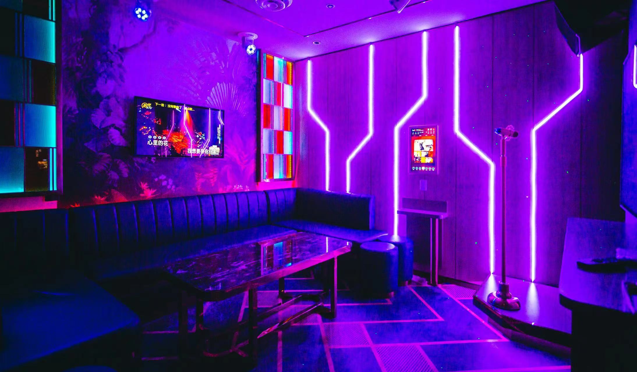 Large karaoke room at V Show with an L-shaped banquette, neon strip lighting on the wall and a standing microphone