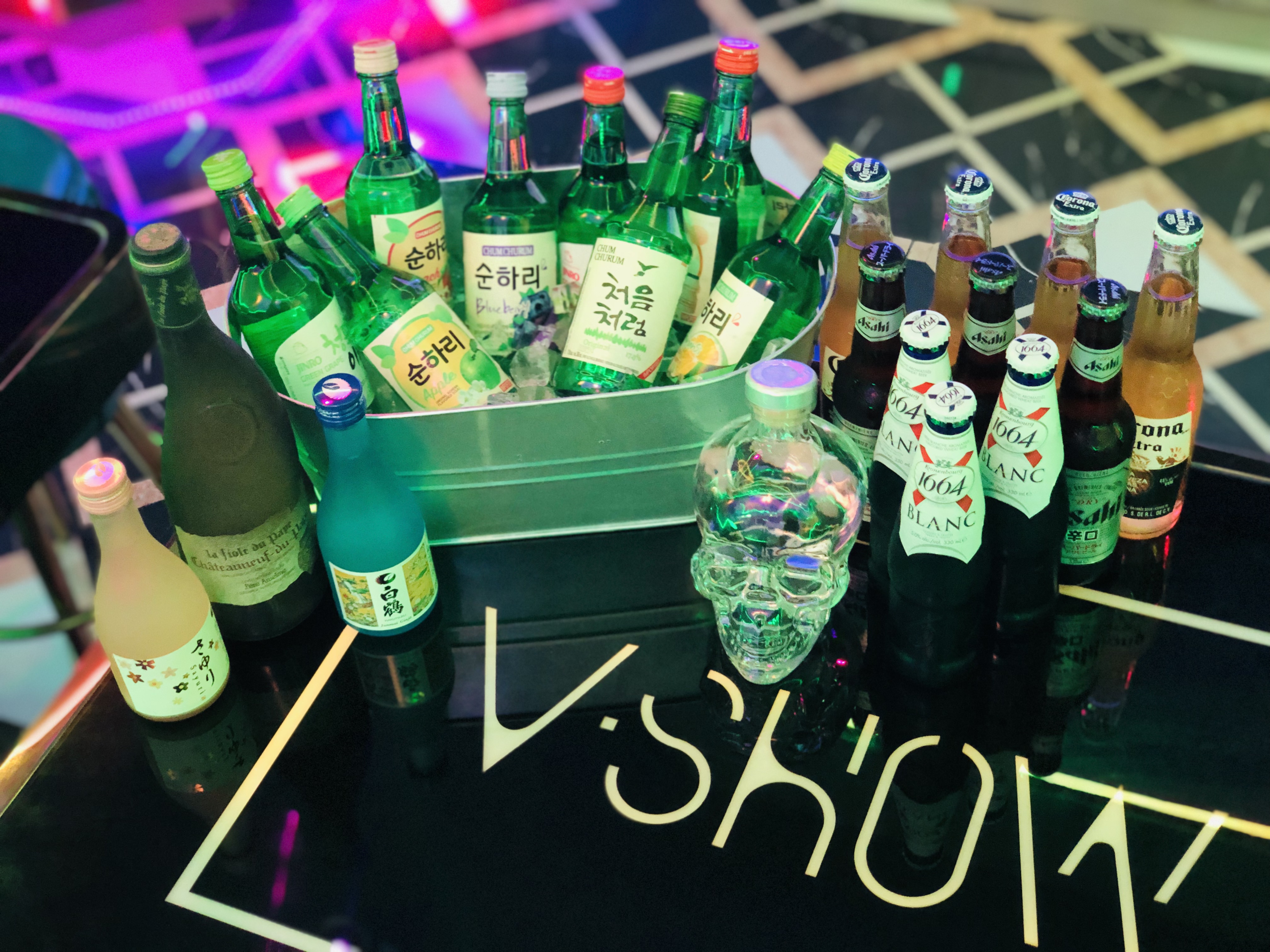 Bottles and glasses set out on a lit V Show table, ready for a group