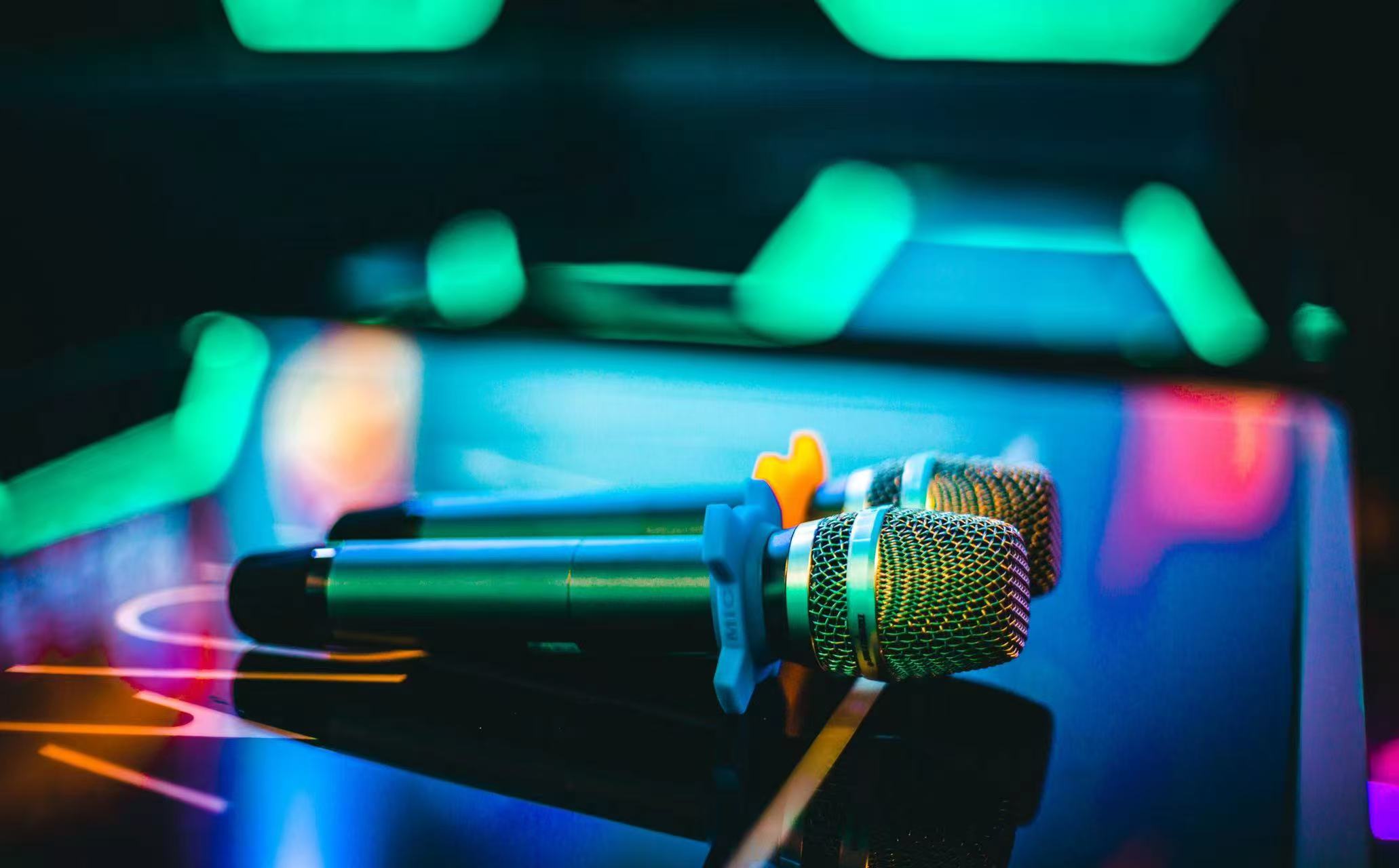 Two V Show microphones resting on a table under green room lighting